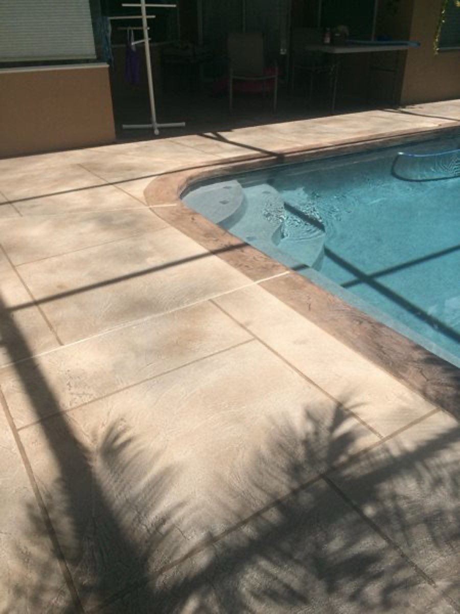 Resurfaced pool deck with a smooth stone-textured coating beside a beachfront condo pool